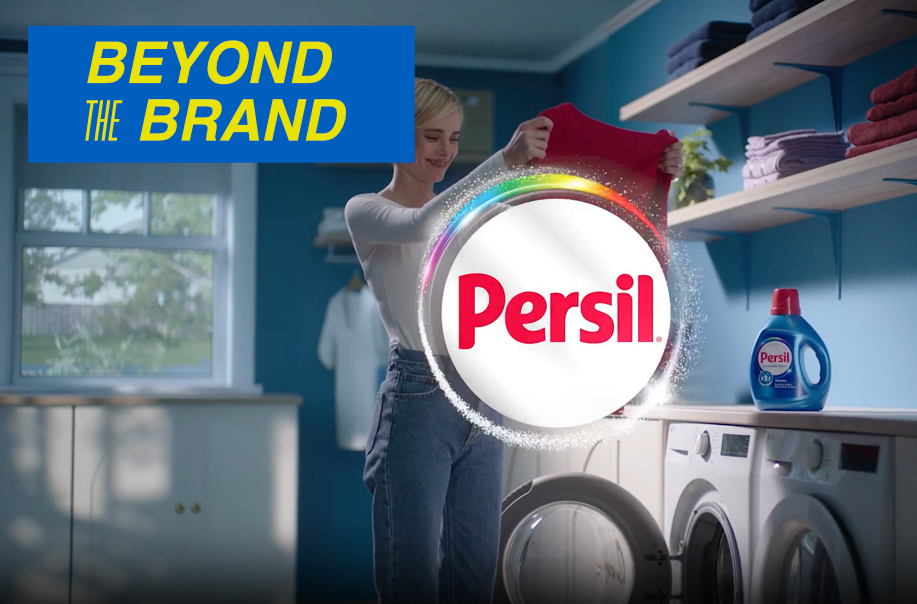 Woman in laundry room holding up clothes with Persil logo overlaid