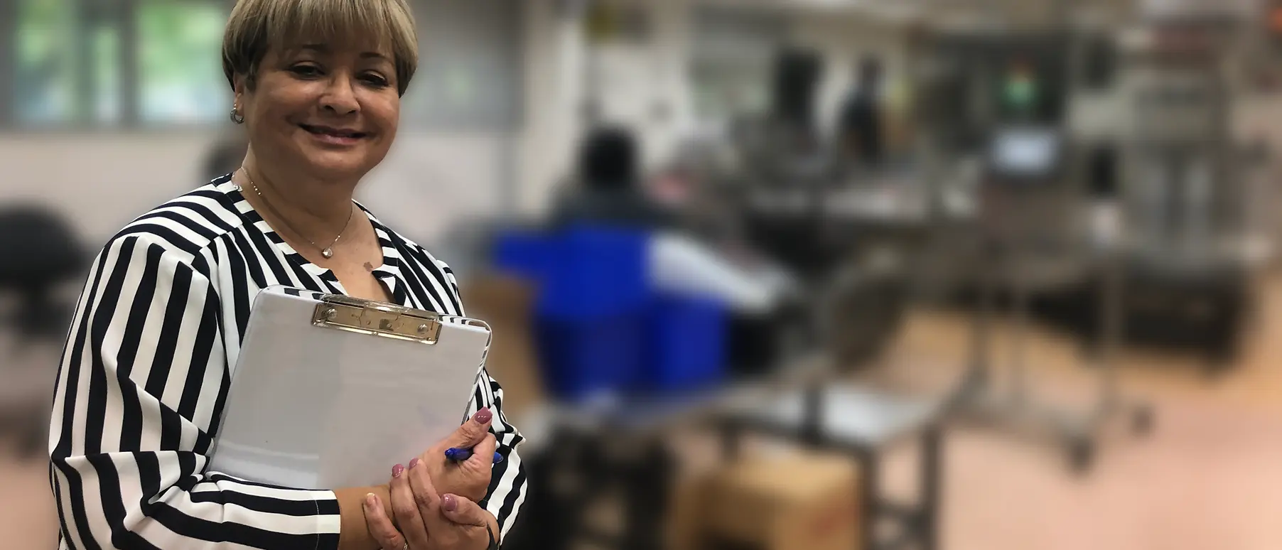 Woman holding clipboard smiling at camera