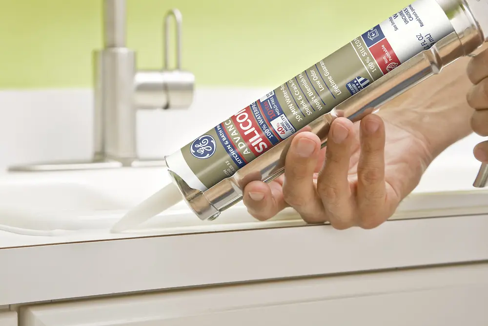 Person holding tube of GE-branded sealant