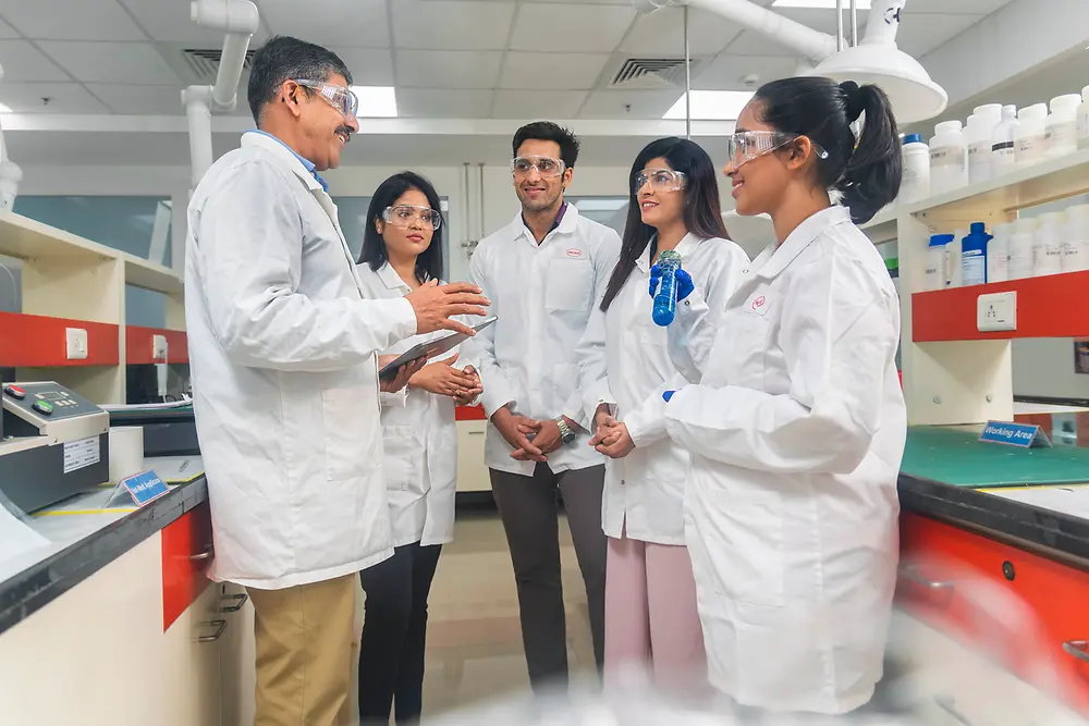 People in lab coats discuss the next steps in a laboratory at the Technology Center Mumbai development center.