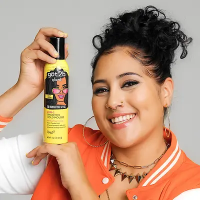Model holding up got2b glued for protective hairstyles yellow bottle against solid background.