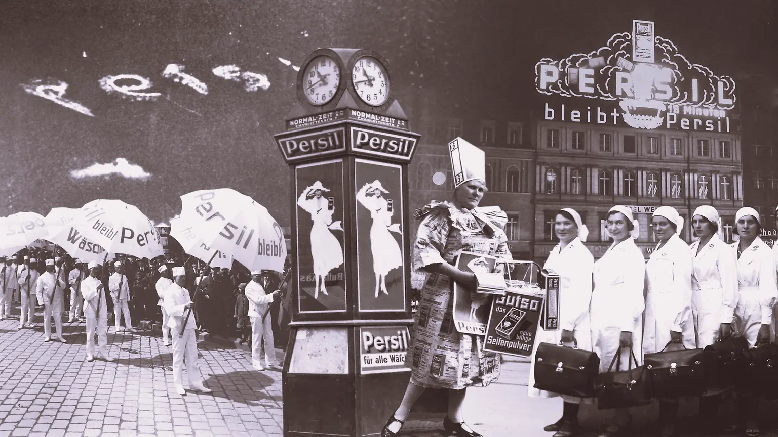 Collage historischer Werbeszenen für Persil aus den 1920er Jahren: Menschen in weißen Uniformen mit Persil-Schirmen, Plakatsäulen mit der „Weißen Dame“ und eine Persiluhr.