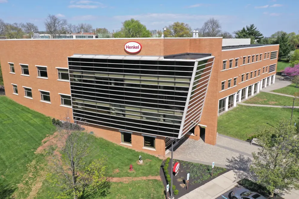 Aerial view of Henkel’s Bridgewater, NJ facility, a brick building with large glass windows, surrounded by green lawns and trees