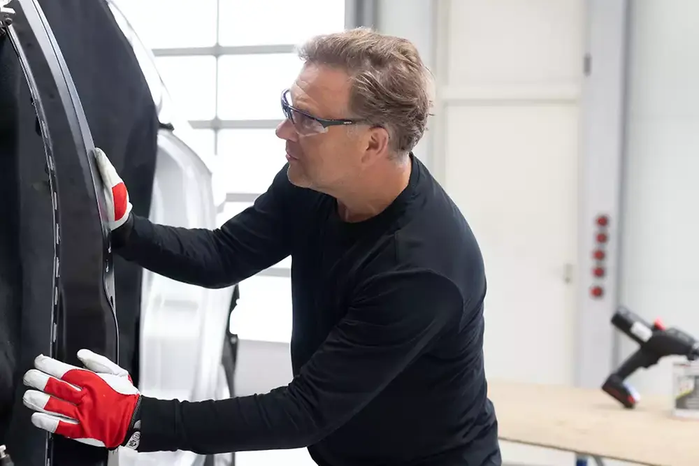 Technician repairing or servicing a vehicle door in an automotive workshop.