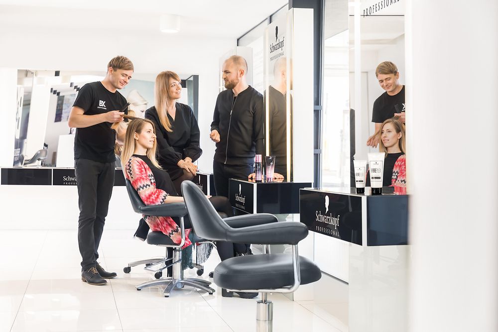salon owner is discussing the new BC Fibre Force product range with Henkel employees after applying it to his client’s hair.