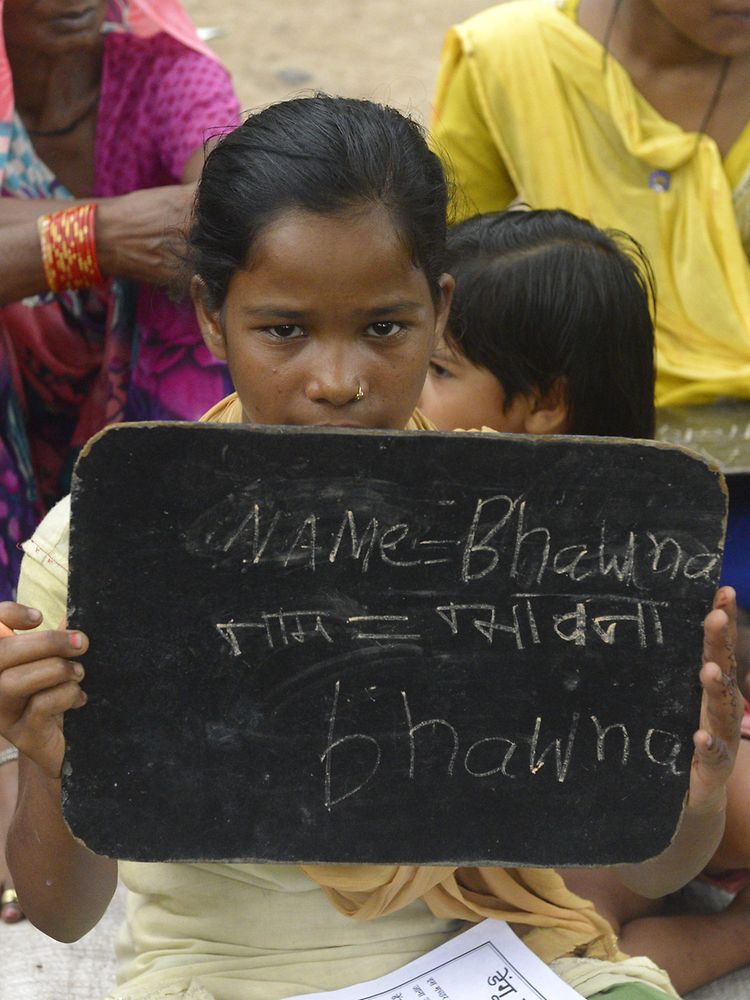 Indian little girl holding up a board with India showing her first written words 